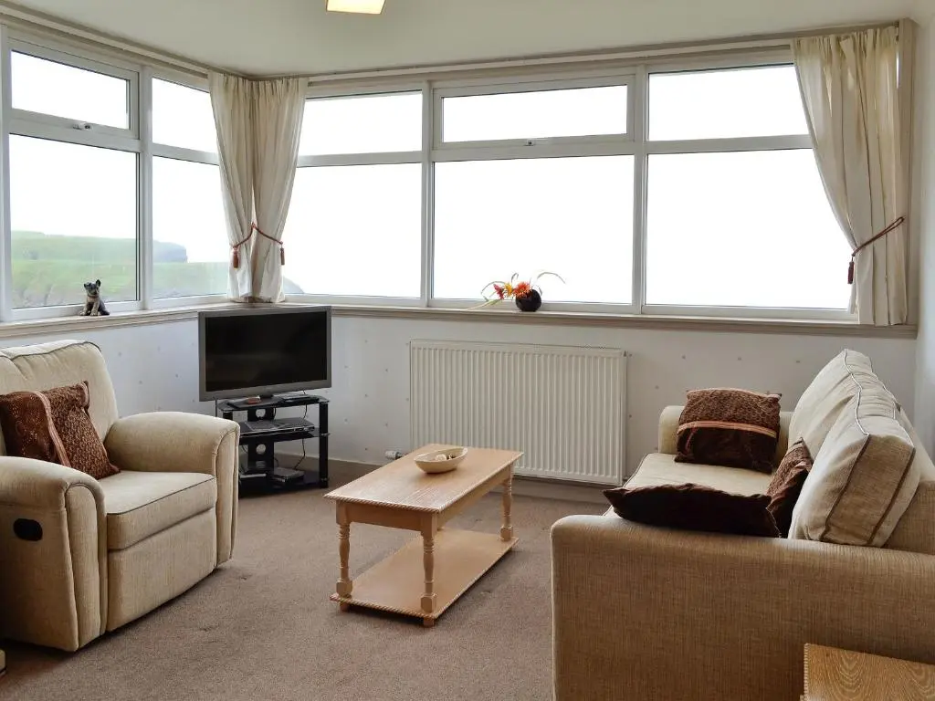 a living room with two chairs and a tv at Mill Shore Cottage - 26817 in Pennan