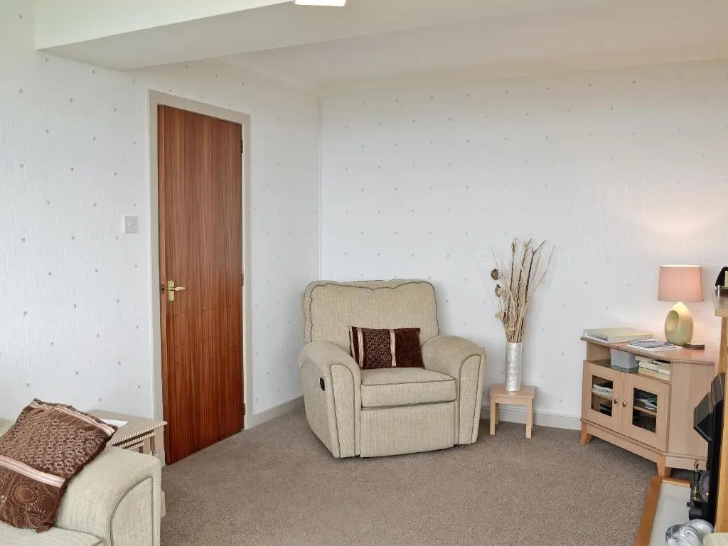 a living room with a chair and a table at Mill Shore Cottage - 26817 in Pennan