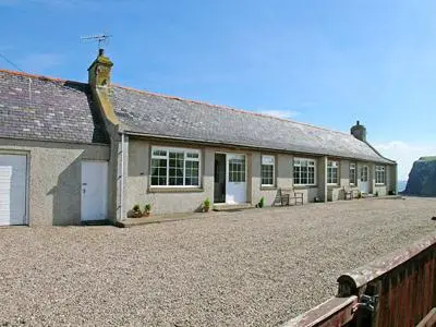 a house with a gravel driveway in front of it at Pennan Lodge - 26818 in Pennan