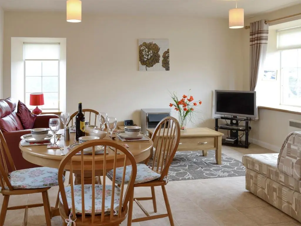 a living room with a table and chairs and a couch at Pennan Lodge - 26818 in Pennan