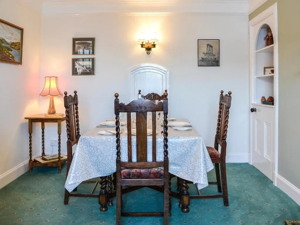 a dining room with a table and chairs and a lamp at St Enodoc in Ullapool