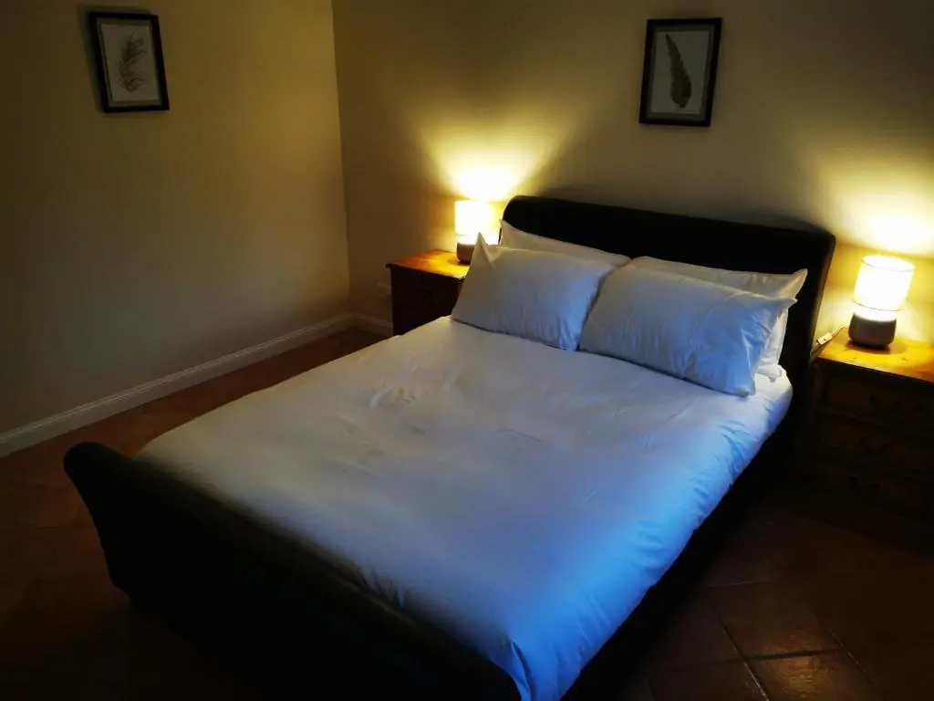 a bedroom with a bed with white sheets and two lamps at Private peacefull pet friendly converted country cottage in Keig