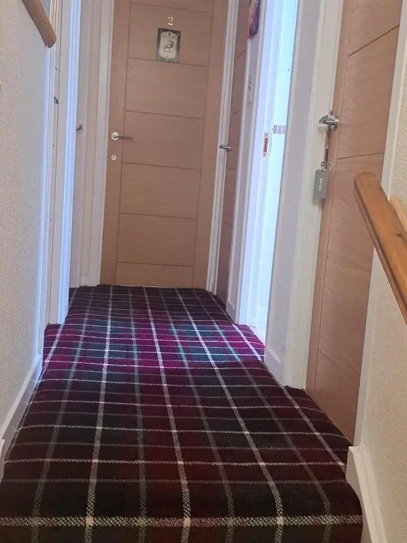 a hallway with a carpeted floor and a door at No 27 in Inverness