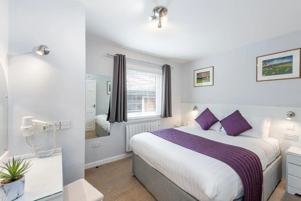a bedroom with a large bed with purple pillows at High Range Self-Catering Chalets in Aviemore