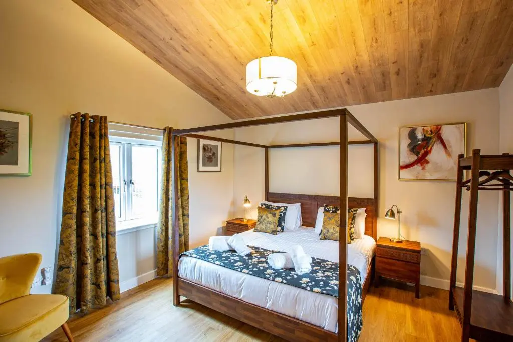 a bedroom with a canopy bed and a wooden ceiling at Breckland Lodge 4 with Hot Tub in Belladrum