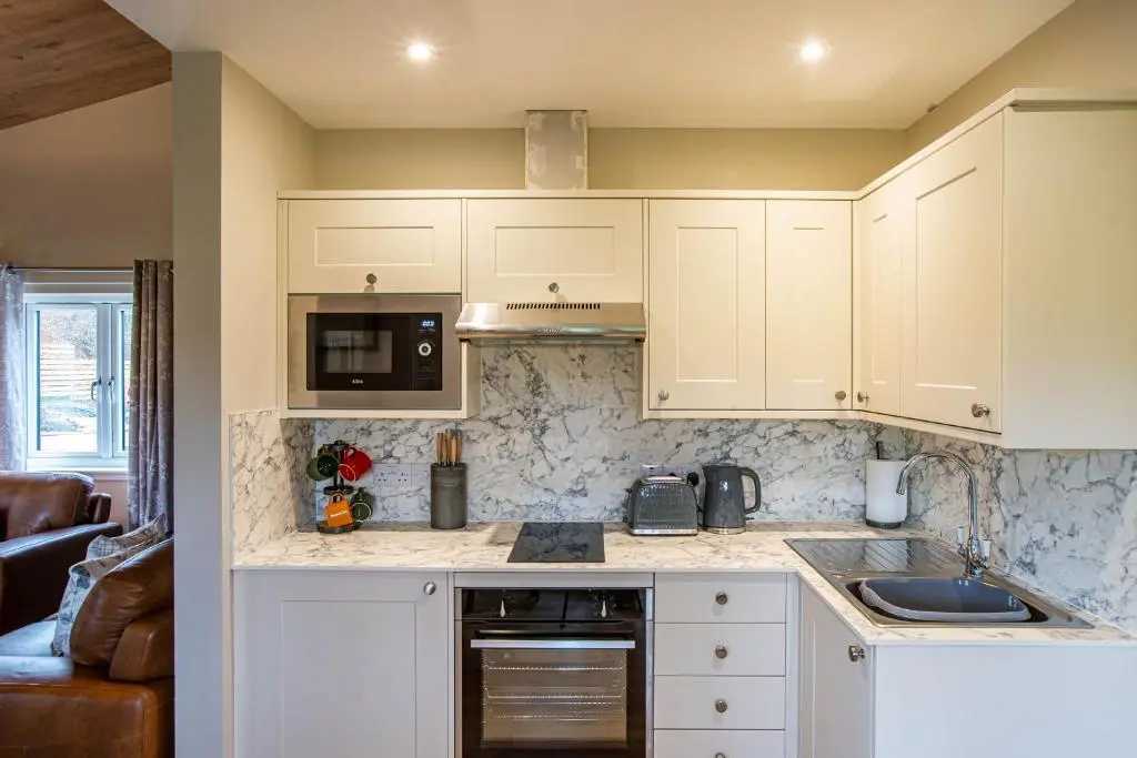 a kitchen with white cabinets and a counter top at Breckland Lodge 4 with Hot Tub in Belladrum