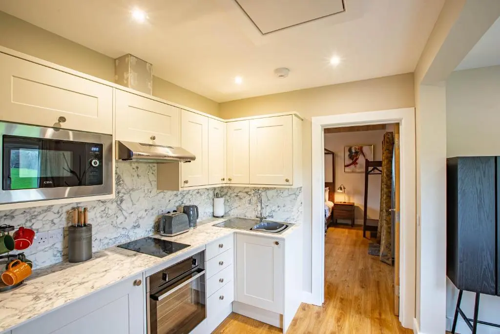 a kitchen with white cabinets and a counter top at Breckland Lodge 4 with Hot Tub in Belladrum