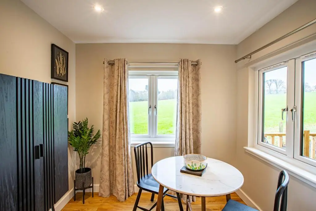 a dining room with a table and a window at Breckland Lodge 4 with Hot Tub in Belladrum