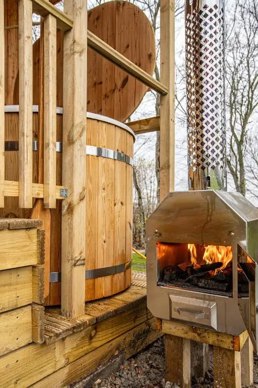 a wood fired oven sitting on a deck with a fence at Breckland Lodge 4 with Hot Tub in Belladrum
