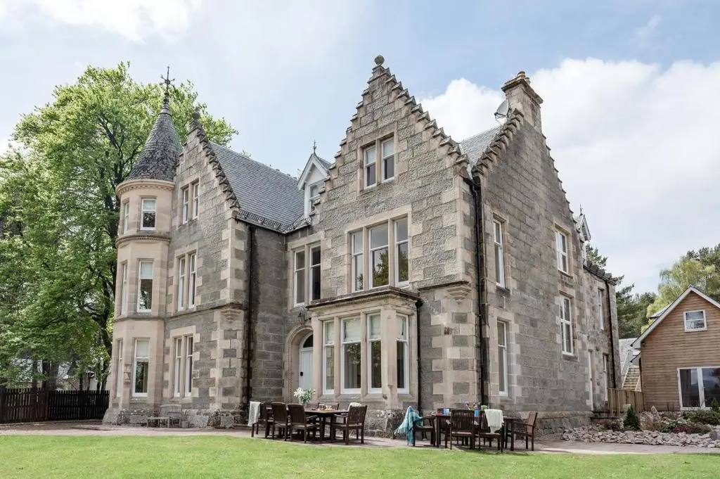 a large stone building with tables in front of it at Craigard Lodge - Seasgair Lodges in Boat of Garten