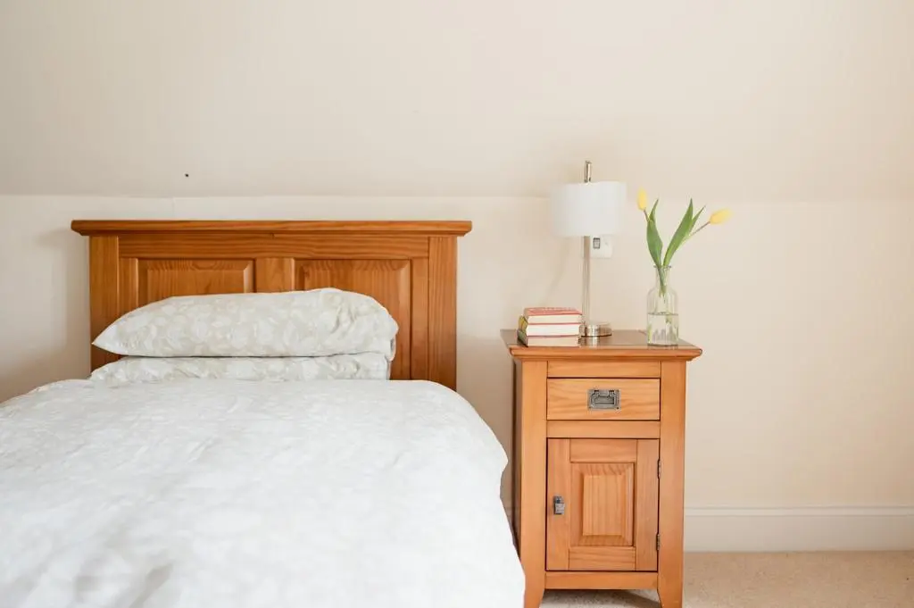 a bedroom with a bed and a wooden night stand at Craigard Lodge - Seasgair Lodges in Boat of Garten