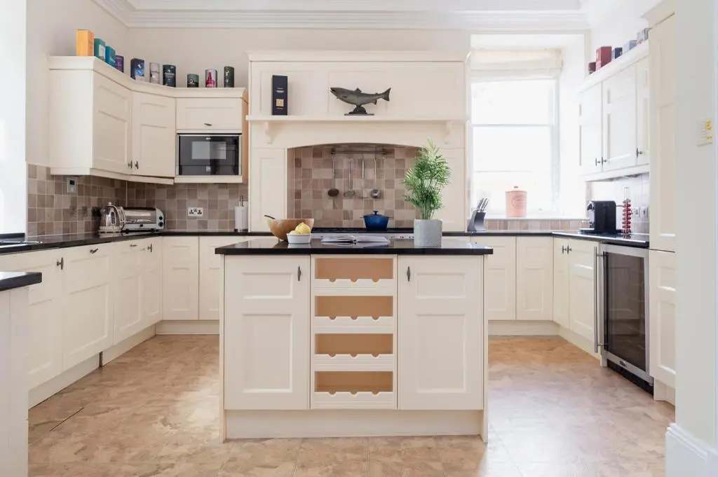 a kitchen with white cabinets and a black counter top at Craigard Lodge - Seasgair Lodges in Boat of Garten