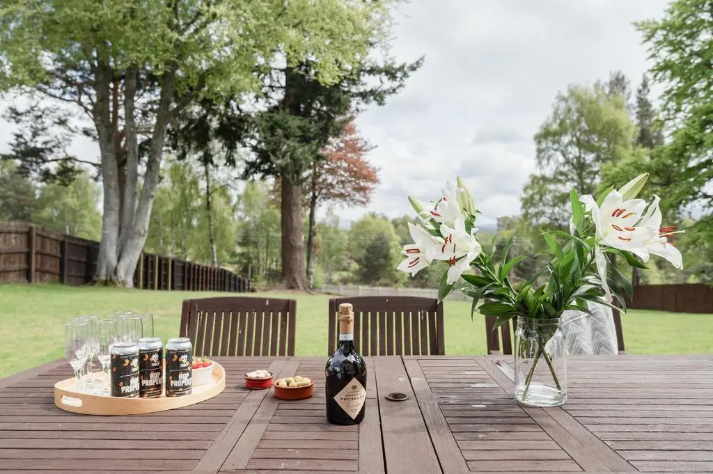 a wooden table with two bottles of wine and glasses at Craigard Lodge - Seasgair Lodges in Boat of Garten
