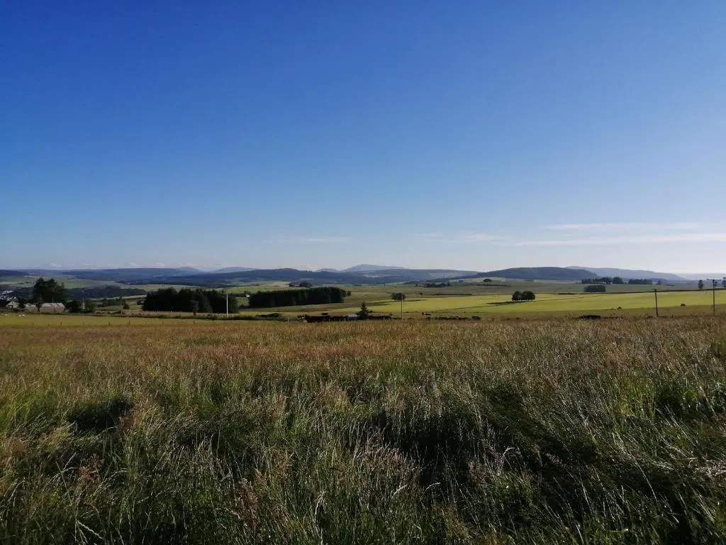 a field of grass with hills in the background at Meikle Balloch in Keith