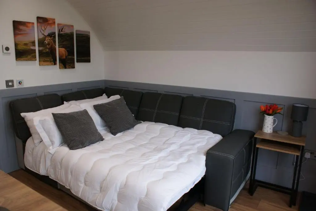 a large bed with white sheets and gray pillows at Meikle Balloch in Keith