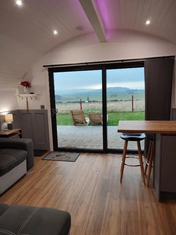 a living room with a table and a large window at Ben Rinnes in Keith