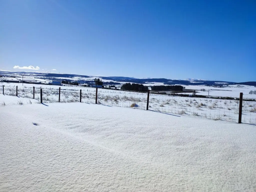 a snow covered field with a fence in the distance at Knockan in Keith