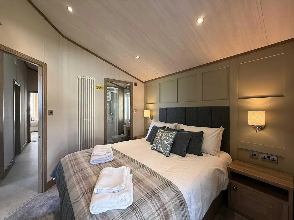 a bedroom with a large bed with two towels on it at Highland Holiday Getaways - The Heilan' Lodge in Embo