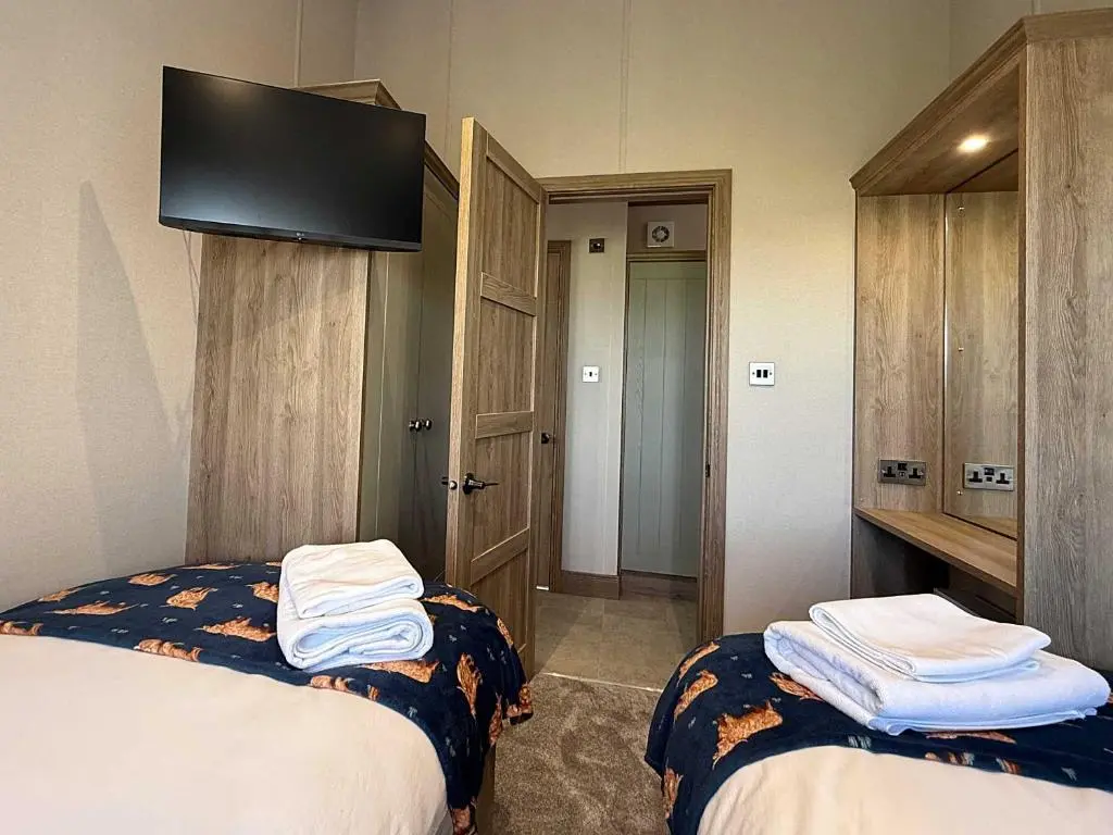 a hotel room with two beds and a flat screen tv at Highland Holiday Getaways - The Heilan' Lodge in Embo