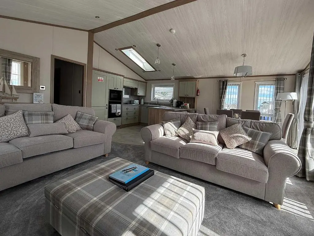 a living room with two couches and a kitchen at Highland Holiday Getaways - The Heilan' Lodge in Embo