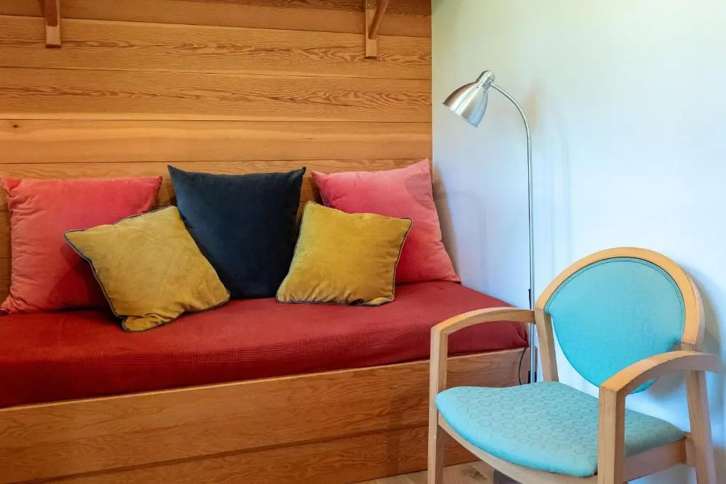 a red couch with colorful pillows and a blue chair at Marcassie Farm Lodges - Willow Studio in Forres