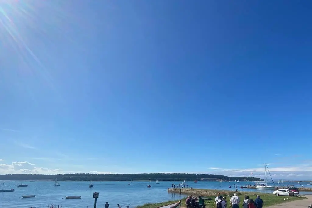 a group of people standing on a beach near a body of water at Lily Cottage - 1 bedroom in Forres