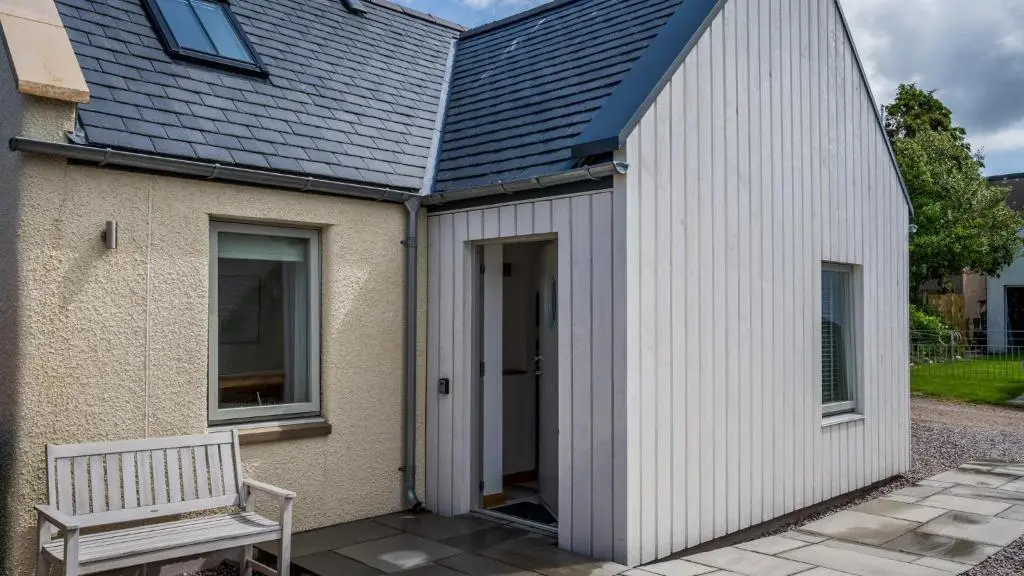 a small white building with a bench next to it at Lily Cottage - 1 bedroom in Forres
