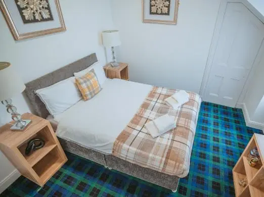a bedroom with a bed with a plaid blanket on it at Nairn View Guest House in Nairn