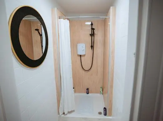 a bathroom with a shower and a tub with a mirror at Nairn View Guest House in Nairn