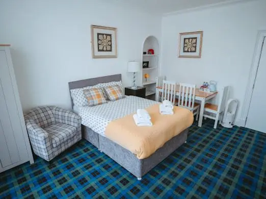 a bedroom with a bed and a chair and a table at Nairn View Guest House in Nairn