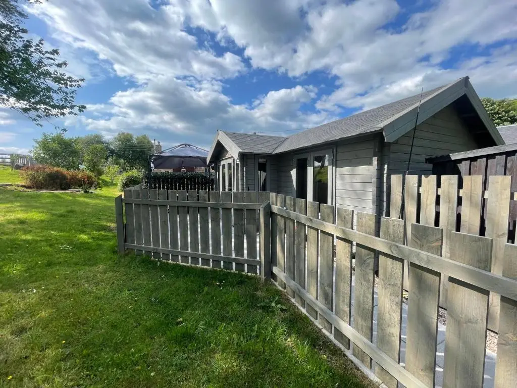 a house with a wooden fence in front of it at Daisy Cabin in Kincardine O\u02bcNeil