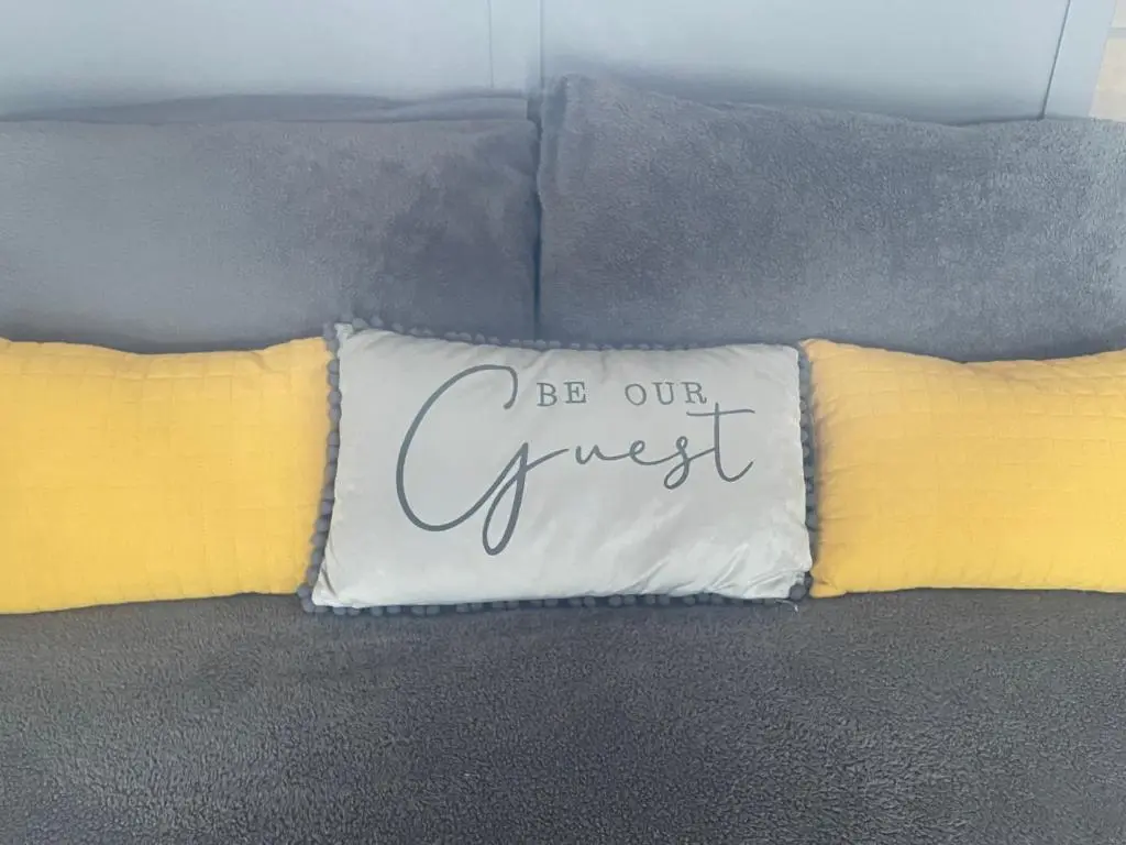 a pillow that says be our guest on a couch at Daisy Cabin in Kincardine O\u02bcNeil