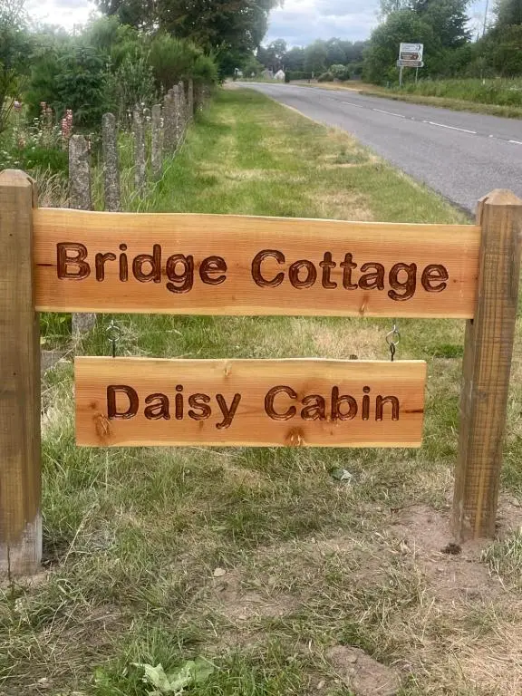 a wooden sign that reads bridge cottage dasy caloth at Daisy Cabin in Kincardine O\u02bcNeil