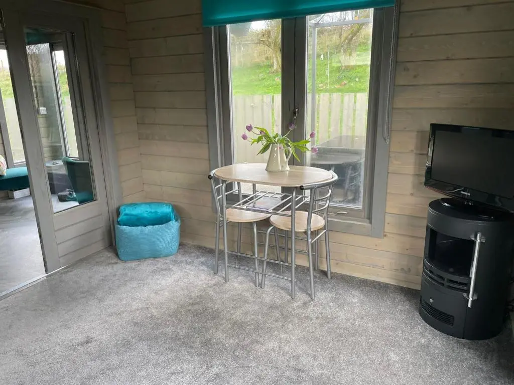 a small table with two stools in front of a window at Daisy Cabin in Kincardine O\u02bcNeil
