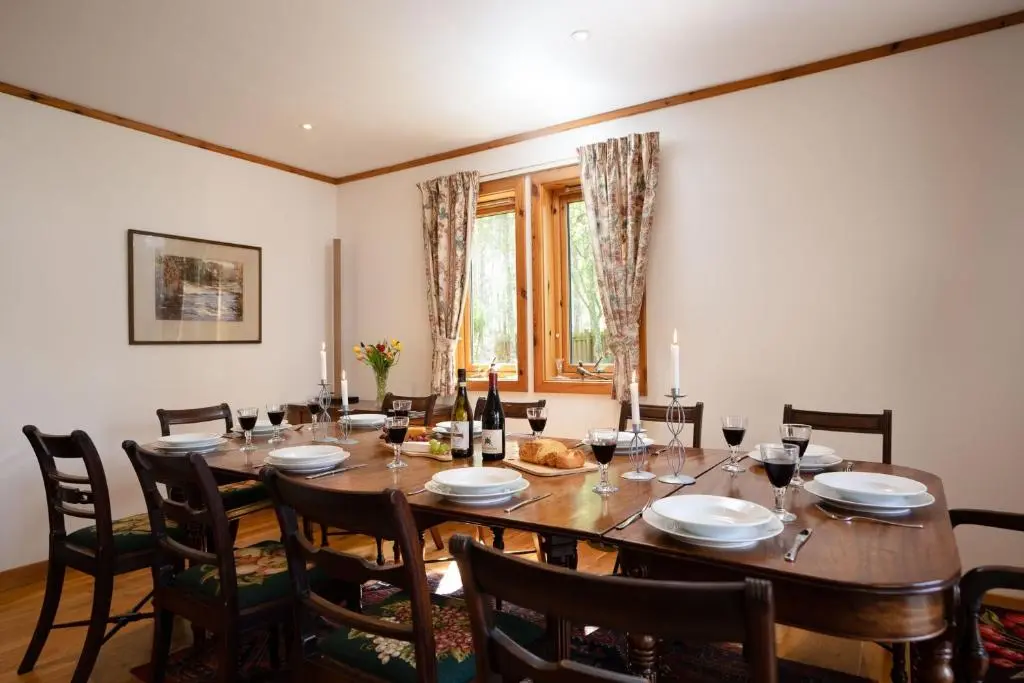 a dining room with a large wooden table and chairs at Langrick in Nethy Bridge
