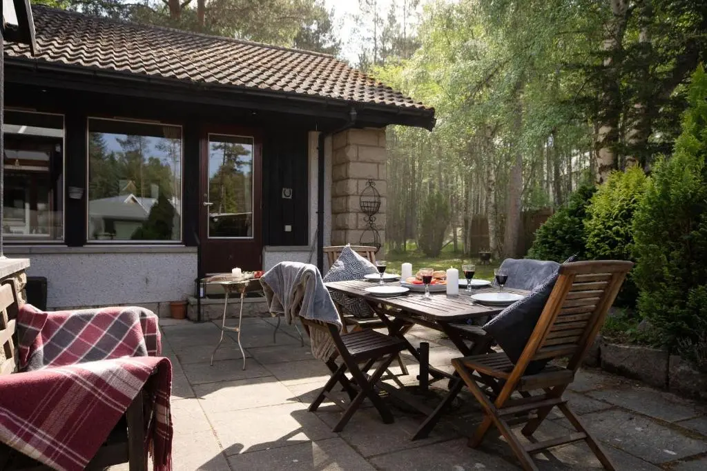 a patio with a table and chairs and a house at Langrick in Nethy Bridge