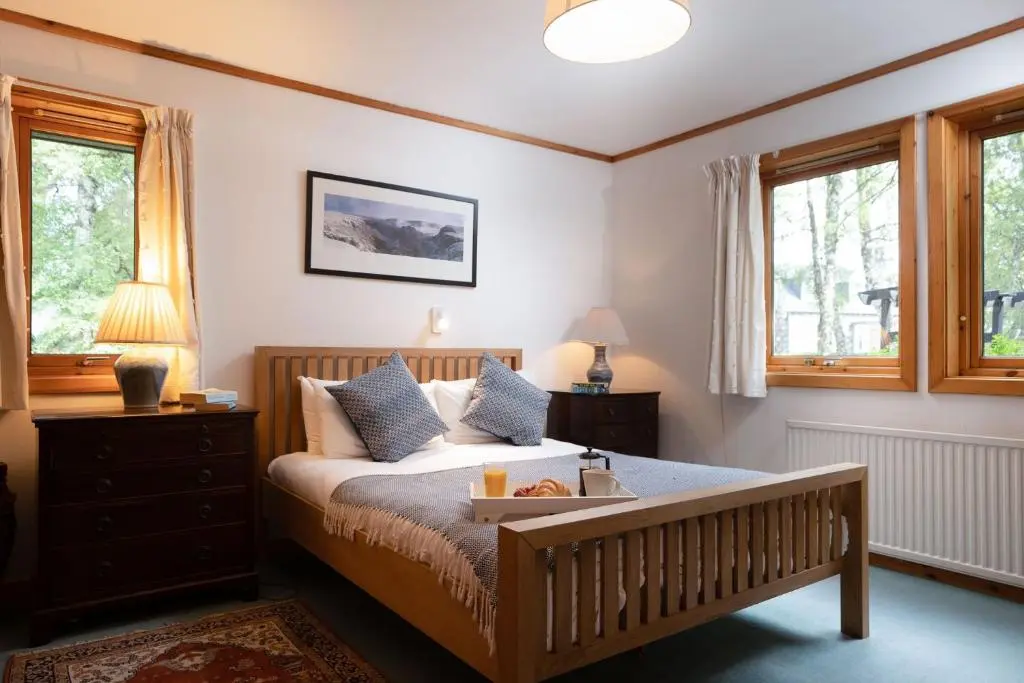 a bedroom with a bed with a tray of food on it at Langrick in Nethy Bridge