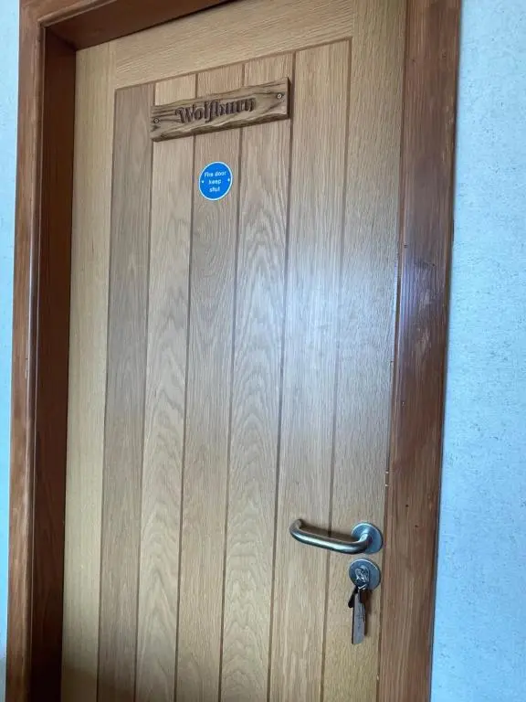 a wooden door with a sign on it at Impala Guest House in Wick
