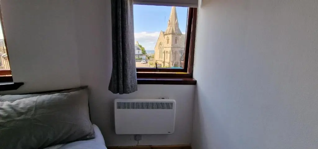 a bedroom with a window and a bed and a radiator at Colin Young Place in Nairn