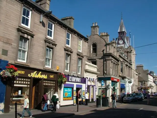 a group of people walking down a city street with buildings at Colin Young Place in Nairn