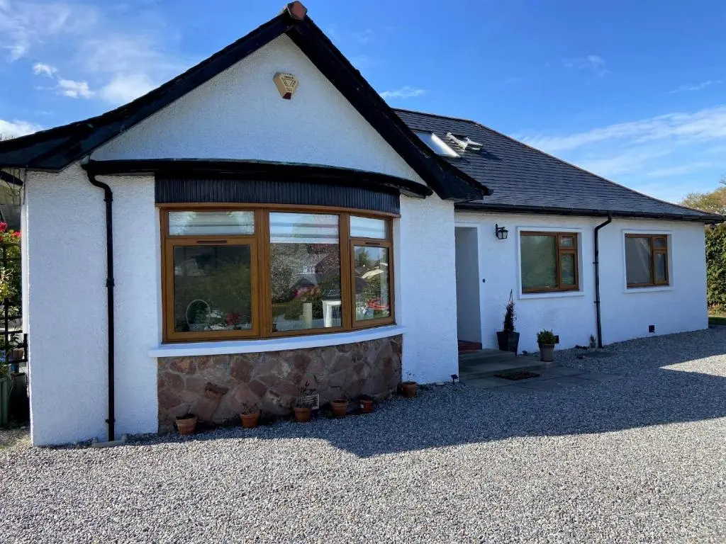 a small white house with a large window at 26 Green Drive Inverness in Inshes