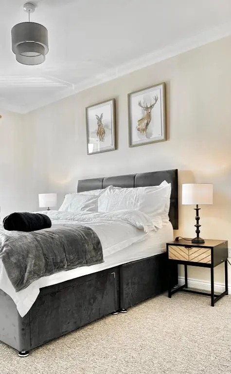 a bedroom with a large bed with two pictures on the wall at Riverview Apartment 2 bed, 2 bath, Free Parking / WiFi in Inverness