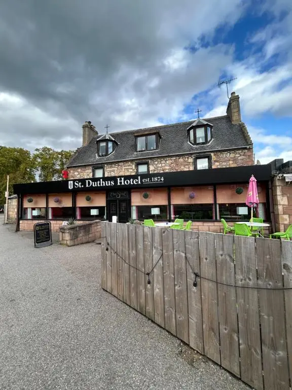 a building with a wooden fence in front of it at St Duthus Hotel Apartment in Tain