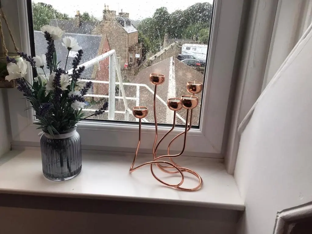 a window sill with flowers and a vase of flowers at St Duthus Hotel Apartment in Tain