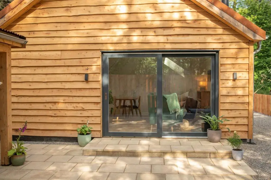 a sliding glass door on a house with a patio at Arbor Nethy Bothy in Cairngorms National Park in Nethy Bridge