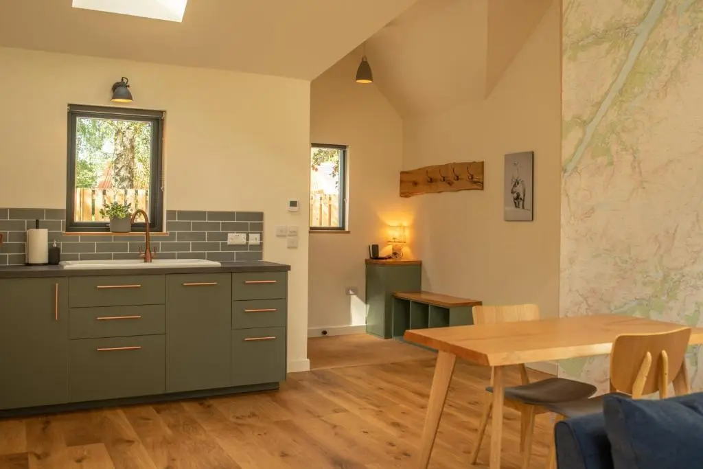 a kitchen with a sink and a table in a room at Arbor Nethy Bothy in Cairngorms National Park in Nethy Bridge