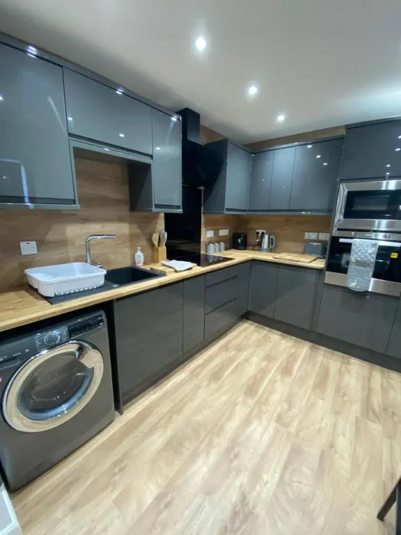 a kitchen with blue cabinets and a washer and dryer at 51 Innes Street Apartment in Inverness