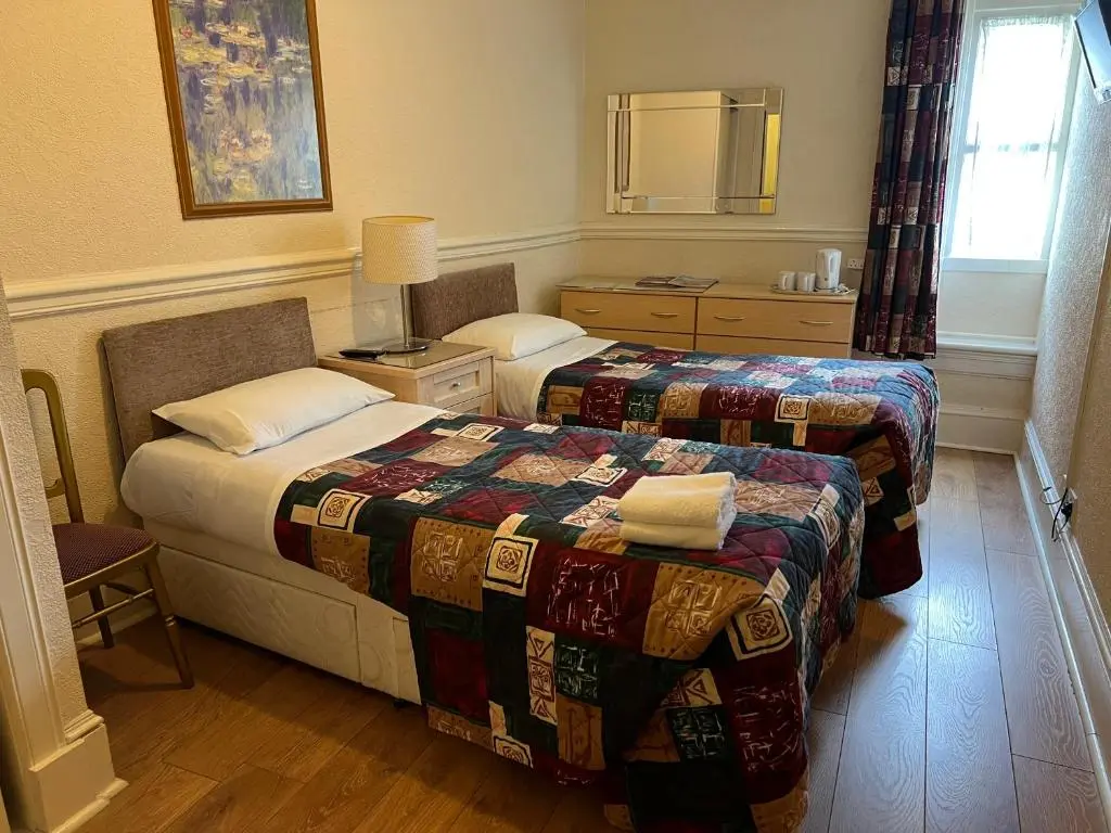 a hotel room with two beds and a mirror at Strathpeffer Hotel in Strathpeffer