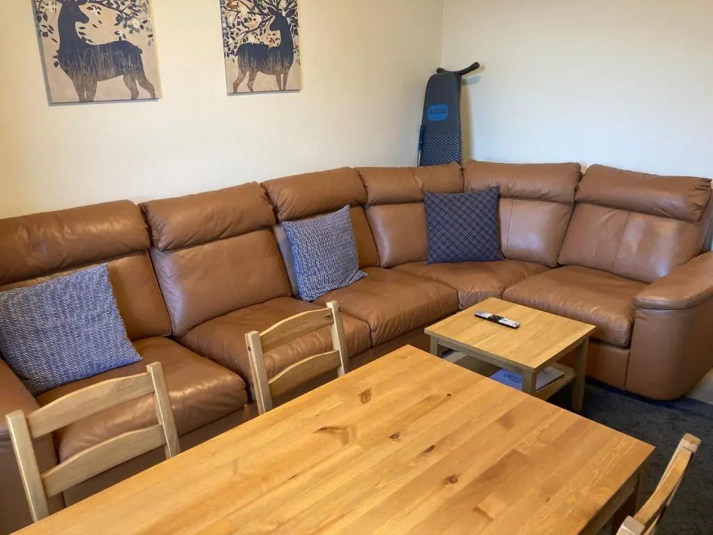 a living room with a brown leather couch and tables at 2 Bed Central Ness Apart - May Court in Inverness