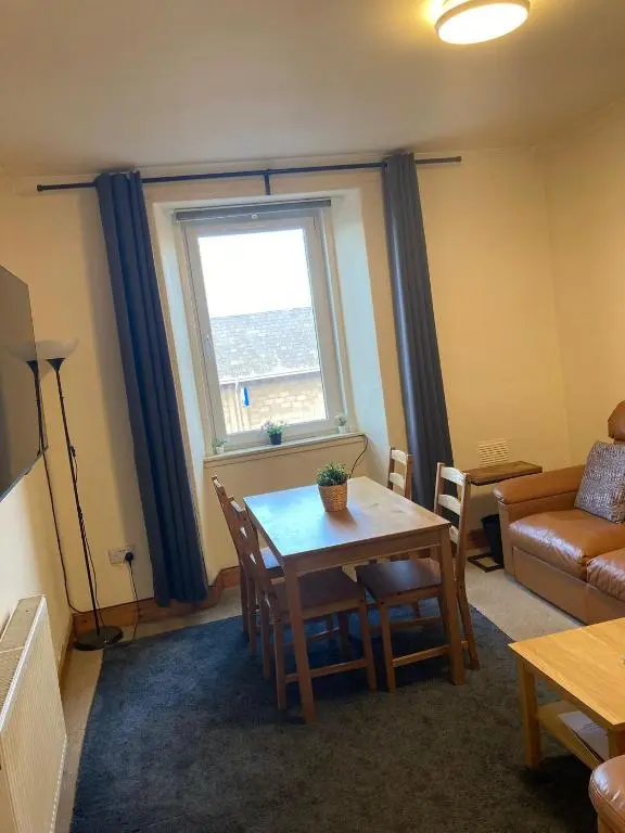 a living room with a table and a window at 2 Bed Central Ness Apart - May Court in Inverness